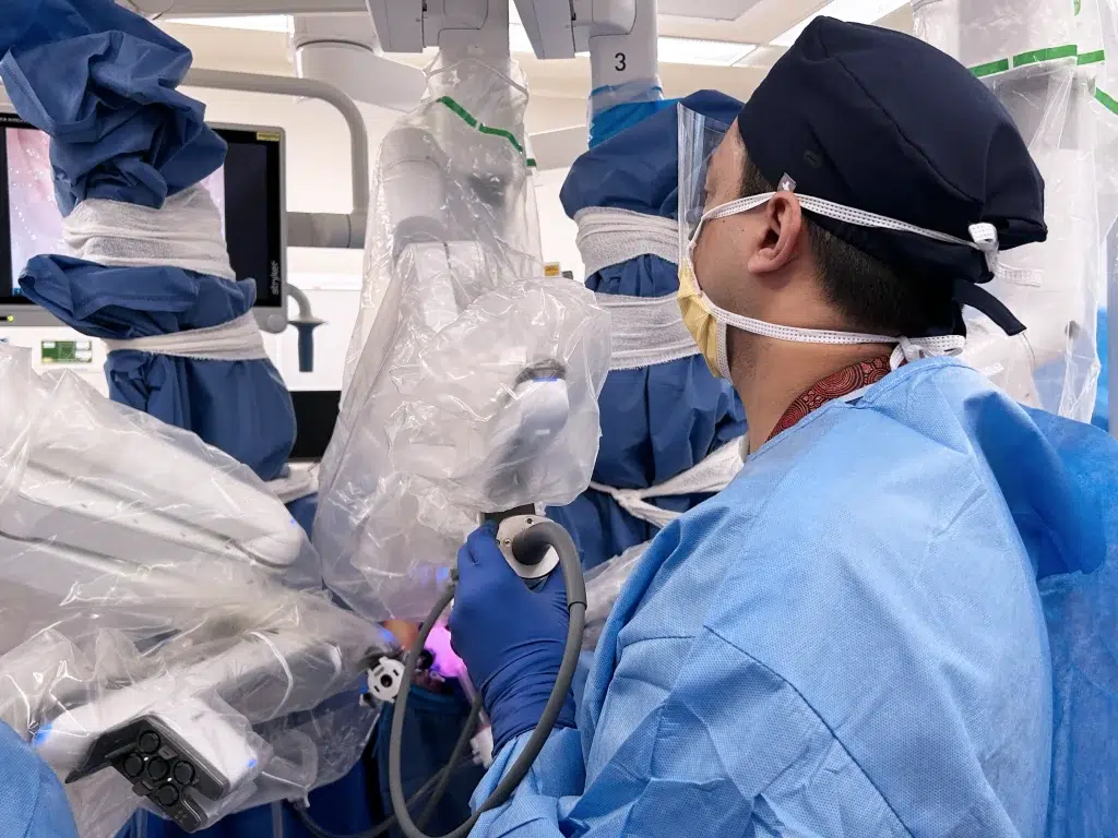 Surgeon operating robotic surgical device in theatre.