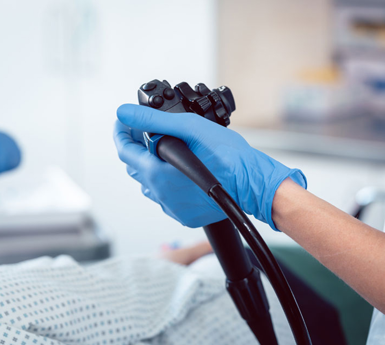 Doctor holding endoscope in hospital room.